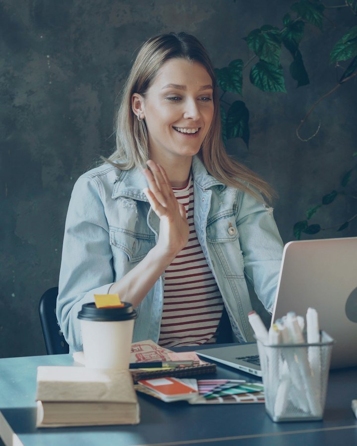 A young woman smiling and waving on a video call